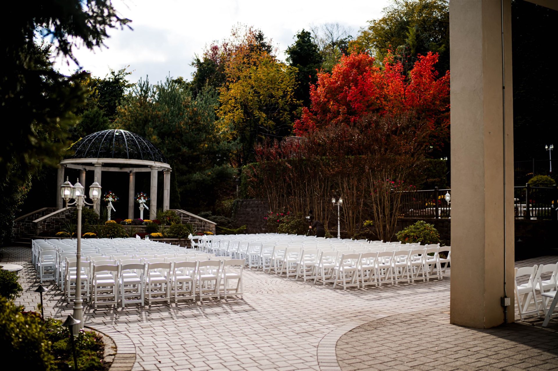 Outdoor ceremony gazebo with fall foliage and white chairs