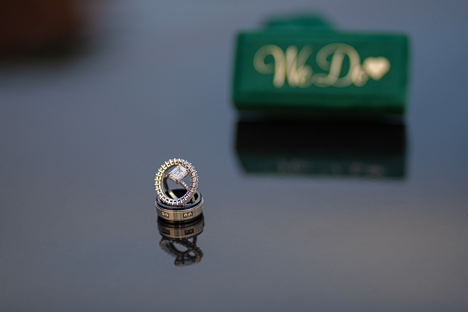 Wedding rings stacked on we-do box with reflection