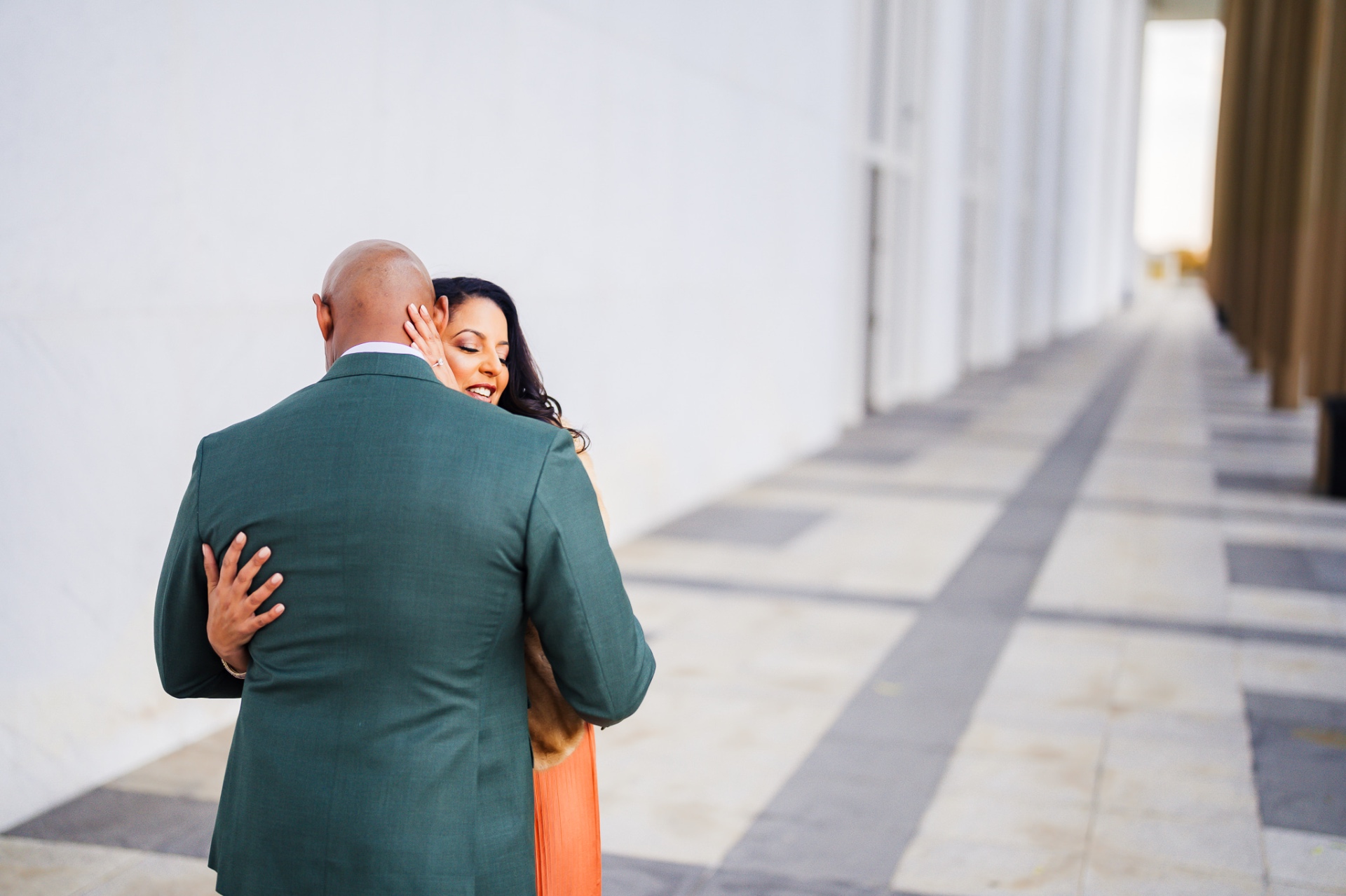 Couple intimate embrace by columns in green suit