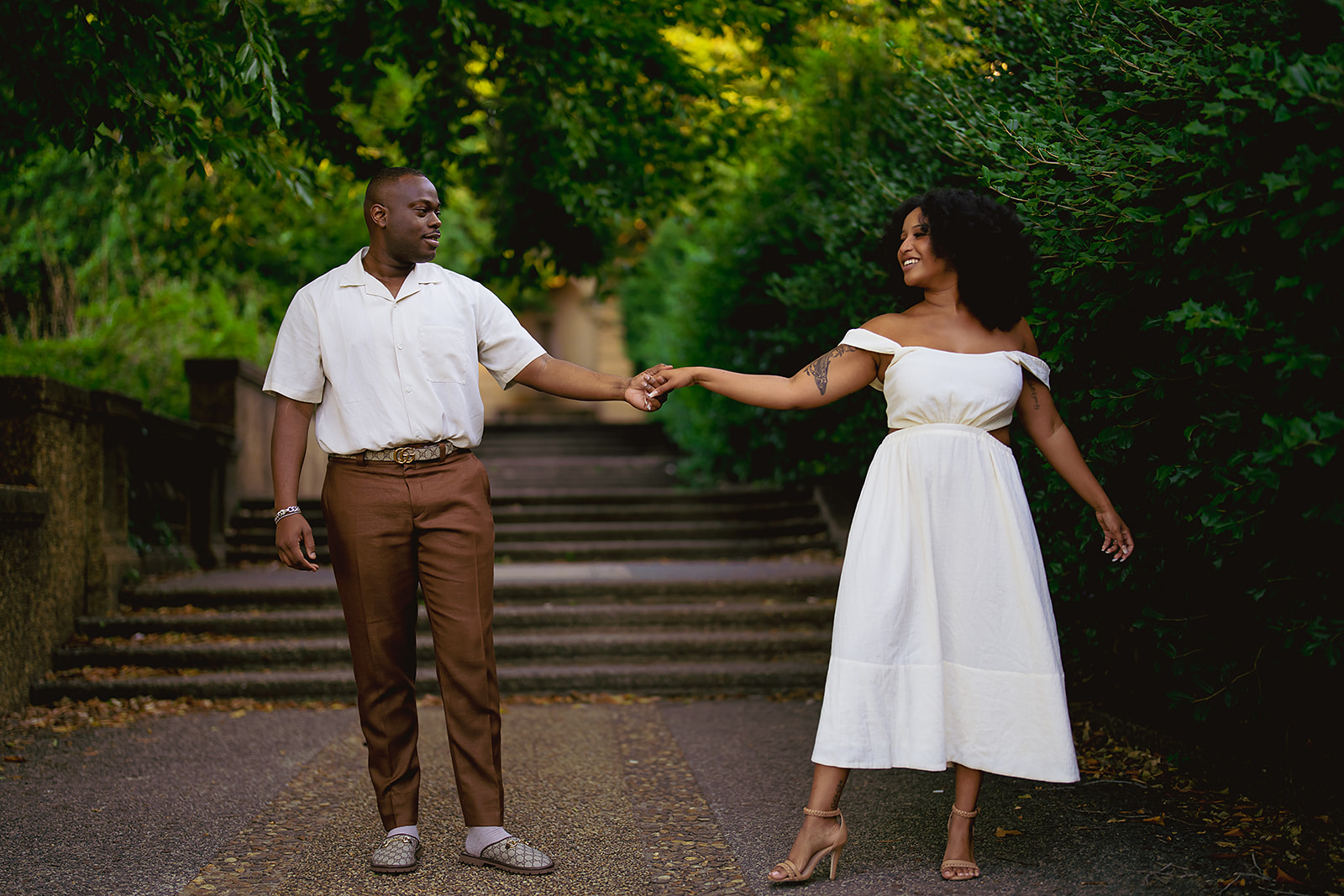 Couple holding hands on garden steps in white dress