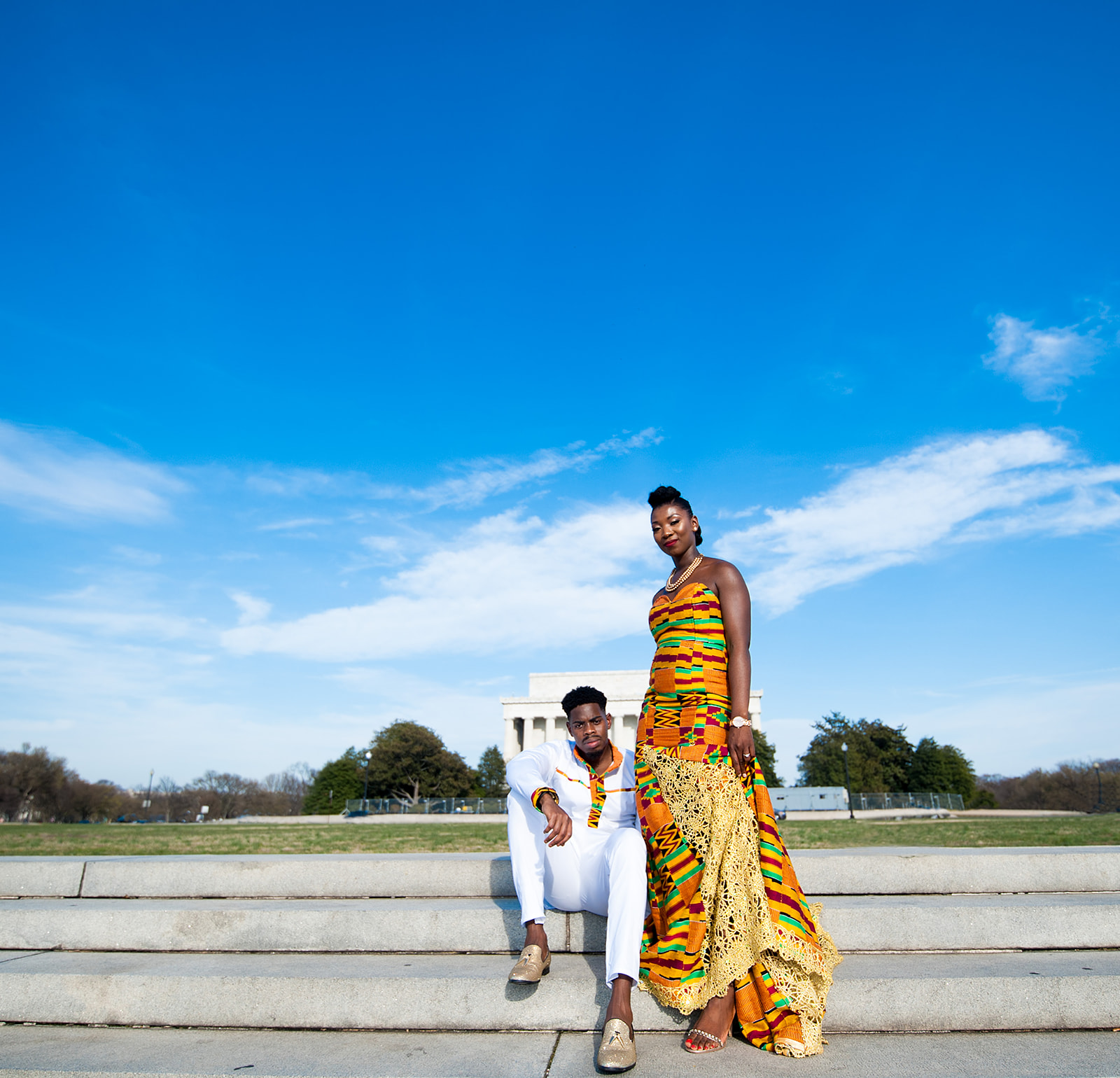 Couple in kente cloth at Lincoln Memorial steps with blue sky DC