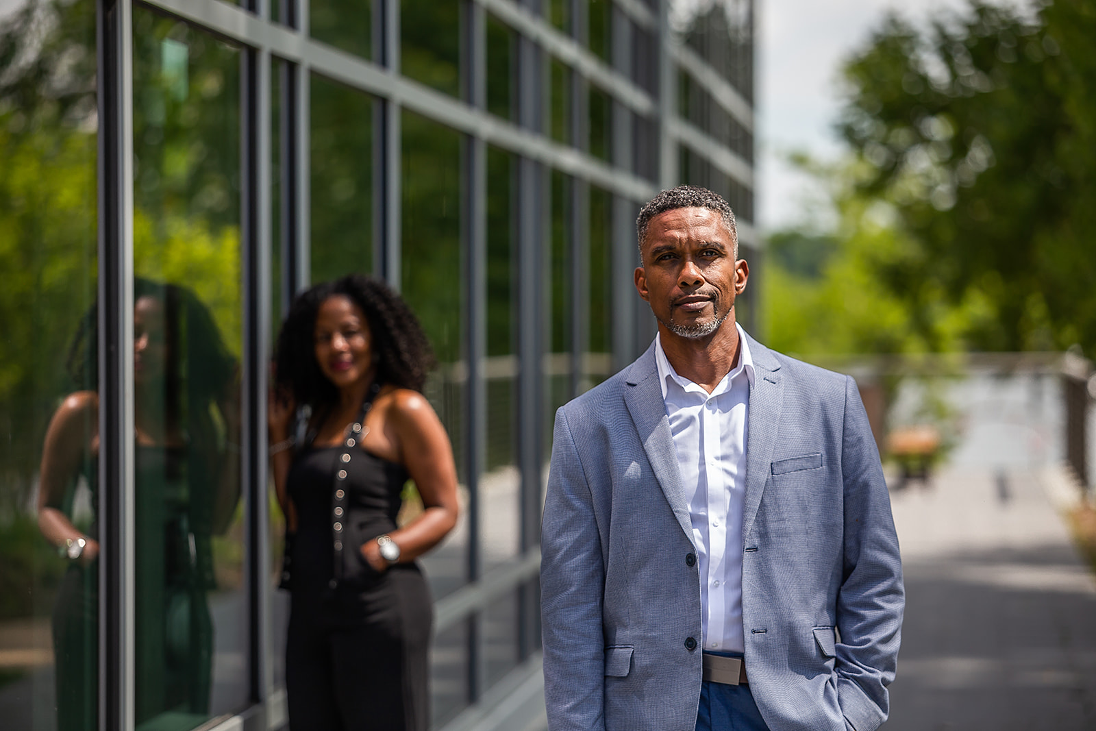 Man in blue blazer at glass building with reflection editorial portrait
