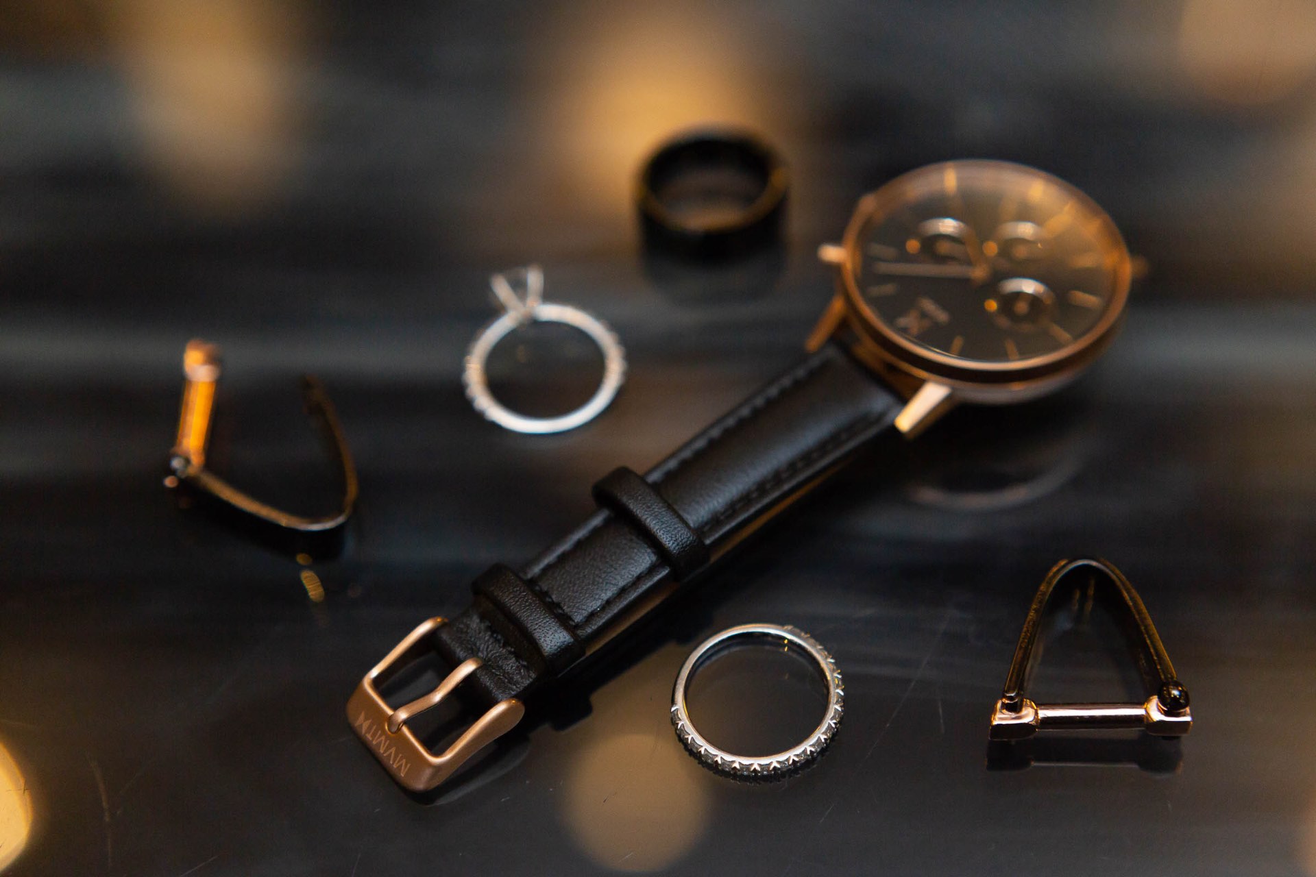 Groom accessories flatlay watch rings cufflinks on dark surface