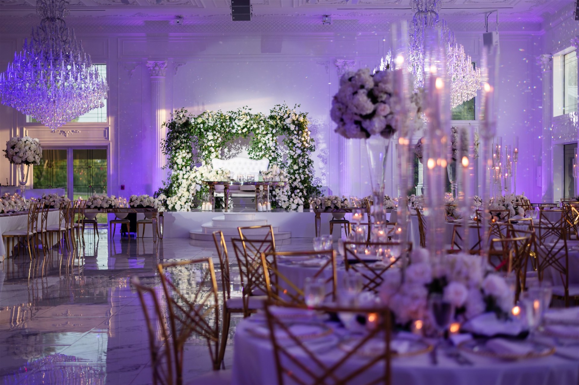 Luxury reception hall purple uplighting crystal chandeliers gold chairs florals