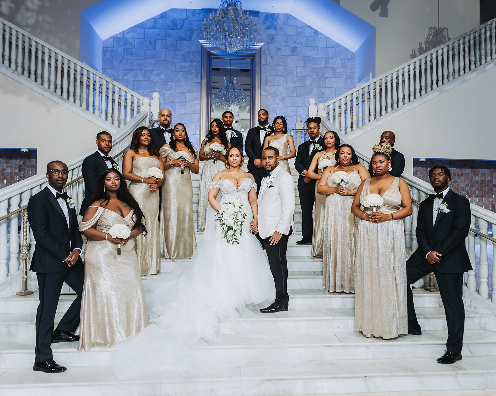 Bridal party on grand marble staircase with chandelier gold bridesmaids
