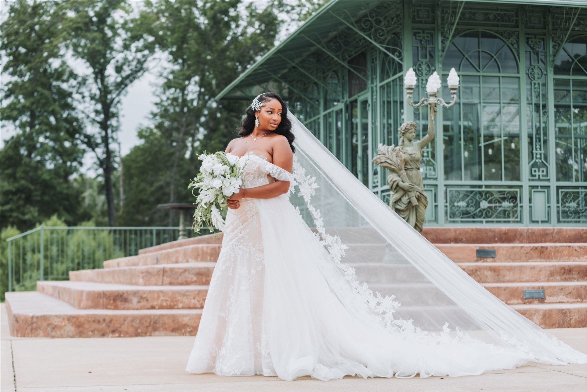 Bride with bouquet and cathedral veil at conservatory steps
