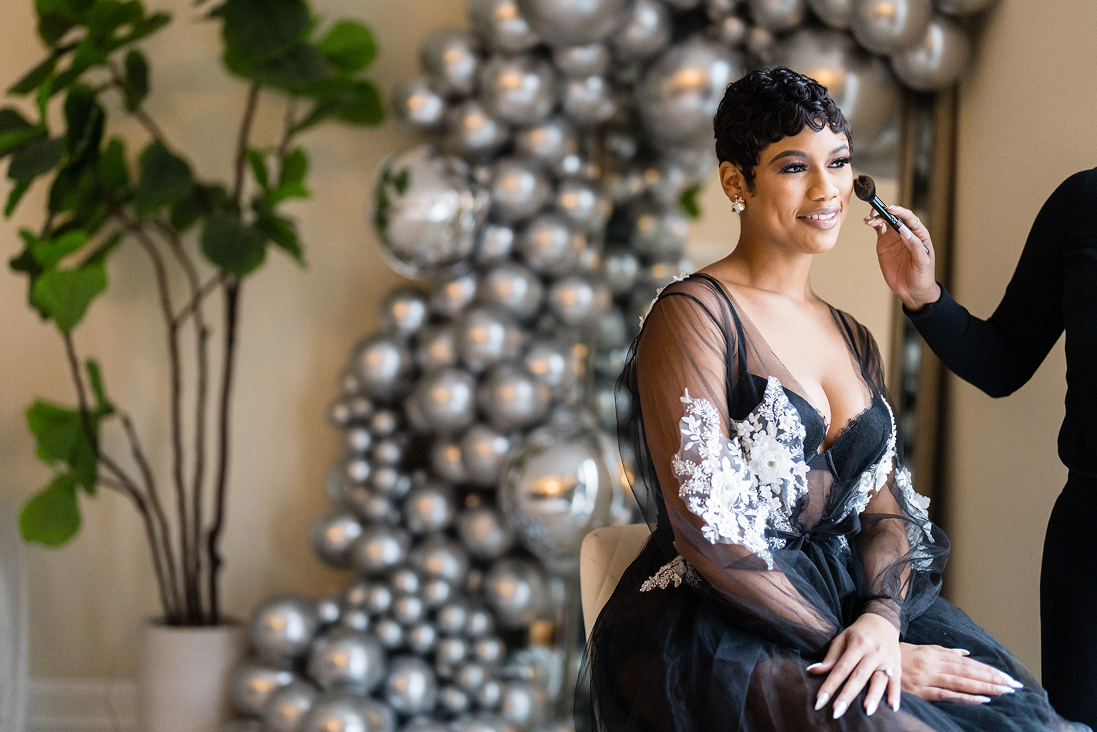 Bride getting makeup in black tulle robe with silver balloons