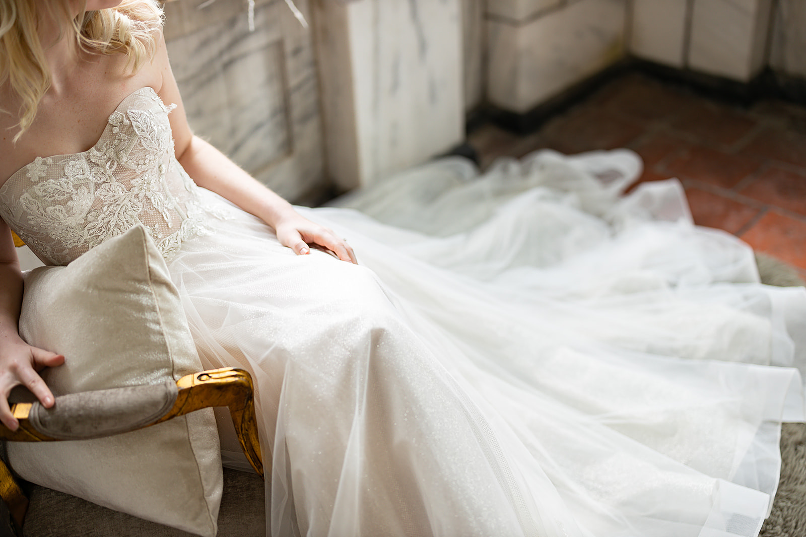 Bride seated in lace gown with tulle train detail