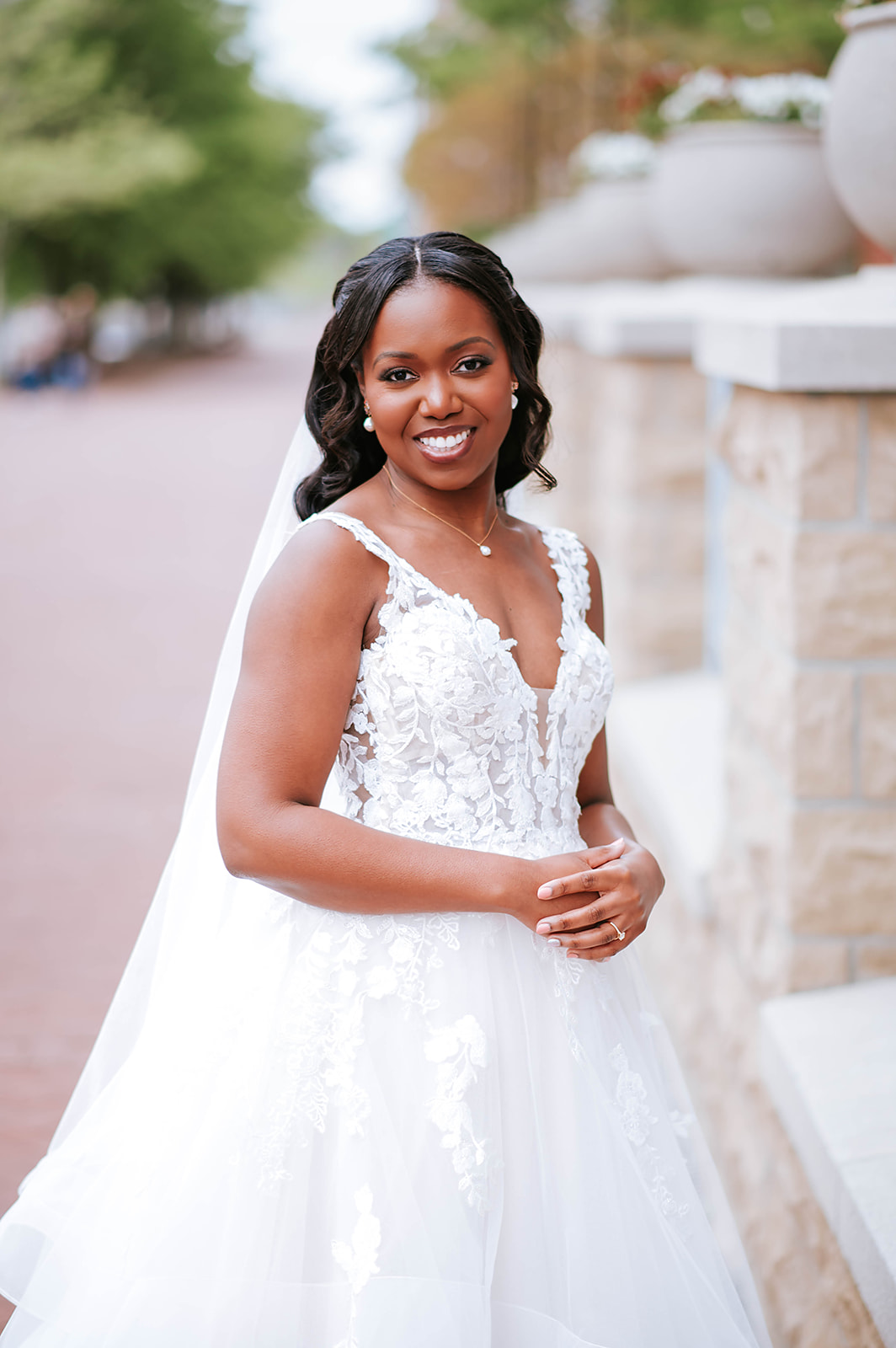 Bride in lace gown smiling by stone balustrade outdoor portrait