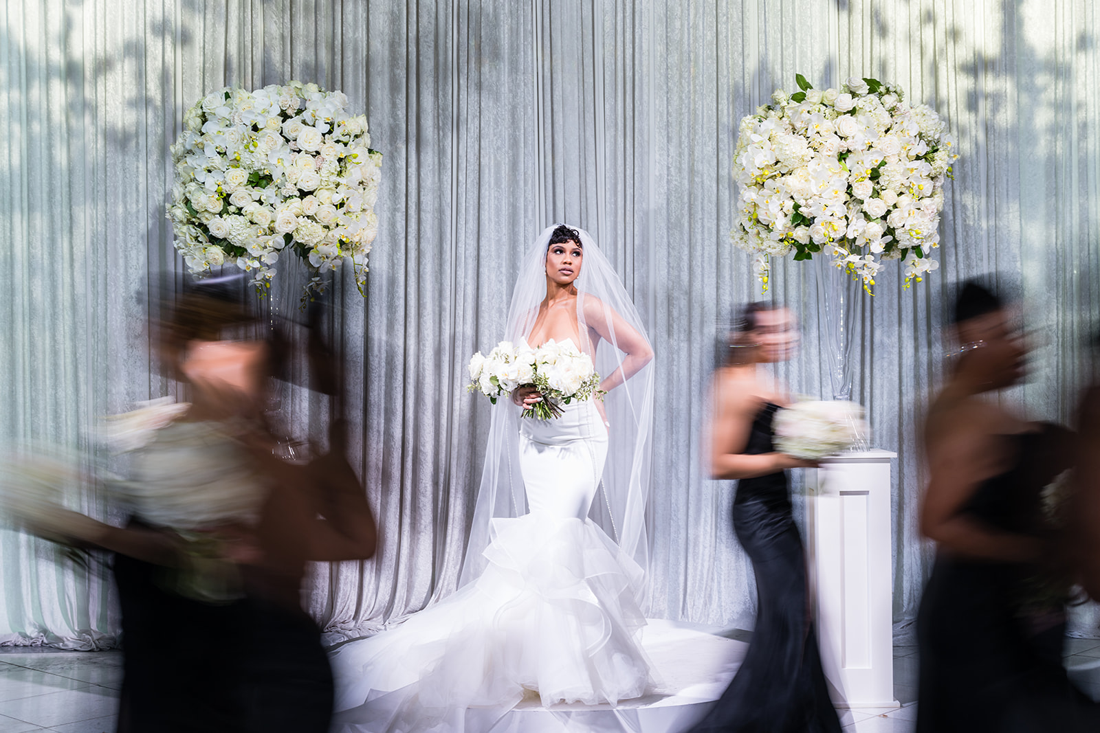 Bride with motion blur bridesmaids white florals silver draping