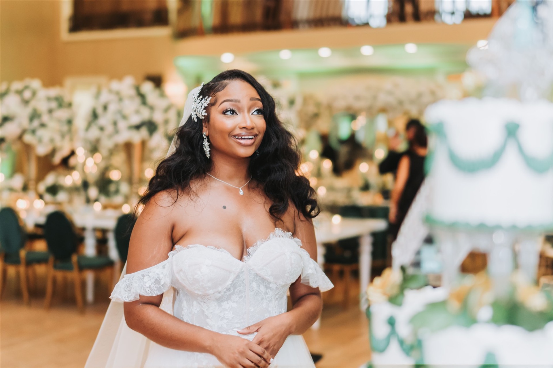 Bride smiling at reception near cake with crystal headpiece