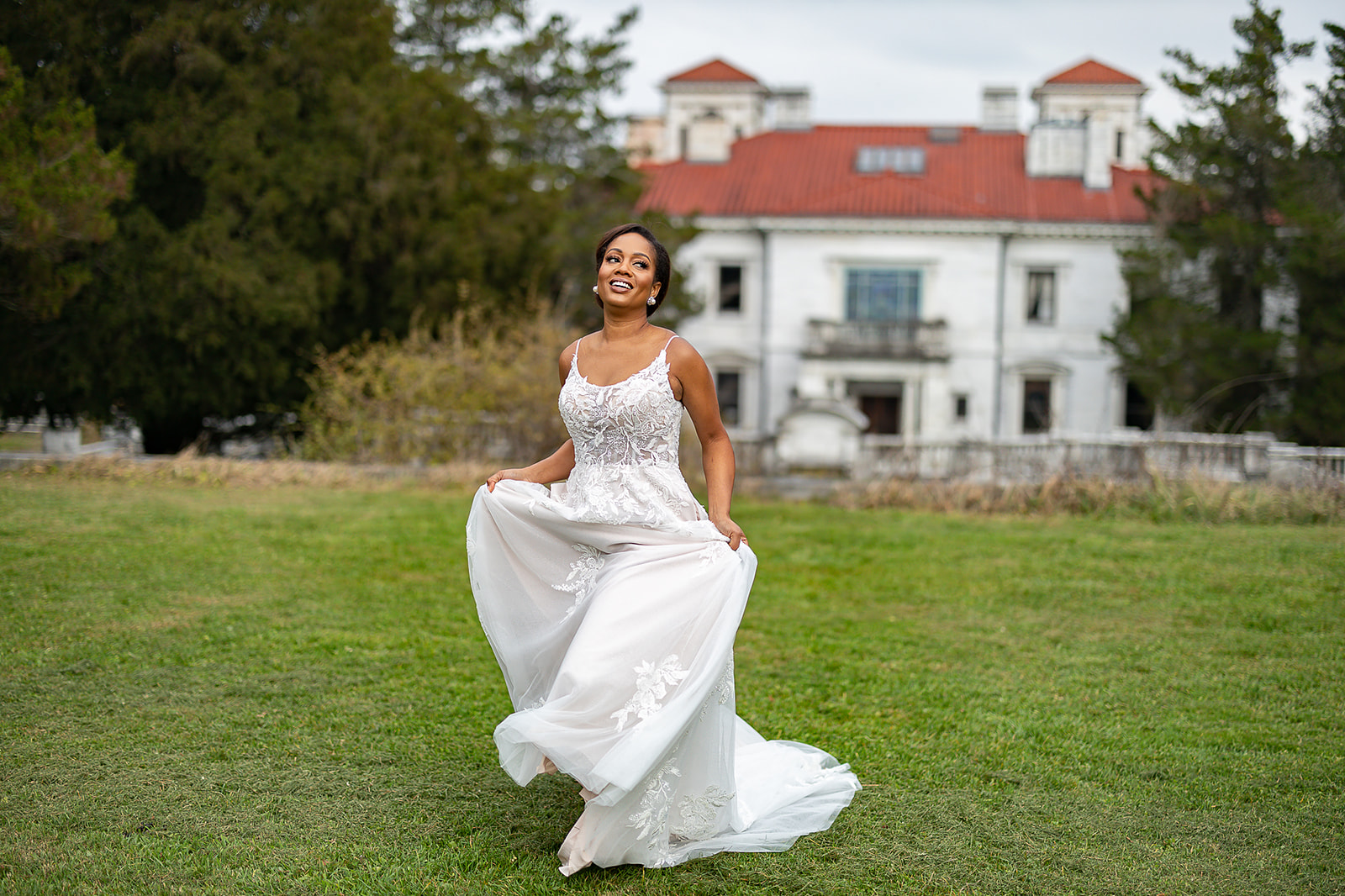 Bride twirling dress on mansion lawn joyful