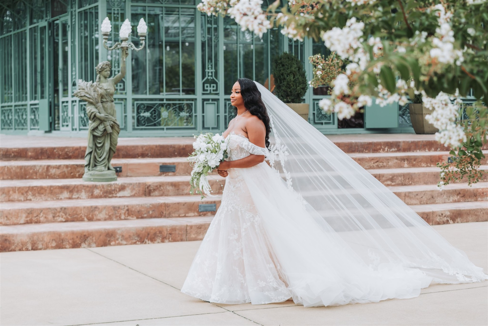 Bride with flowing veil at conservatory with flowers