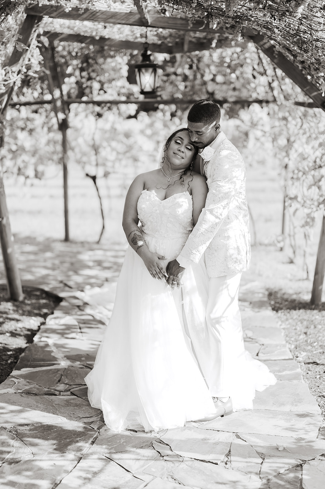 Couple intimate embrace under pergola at vineyard black and white