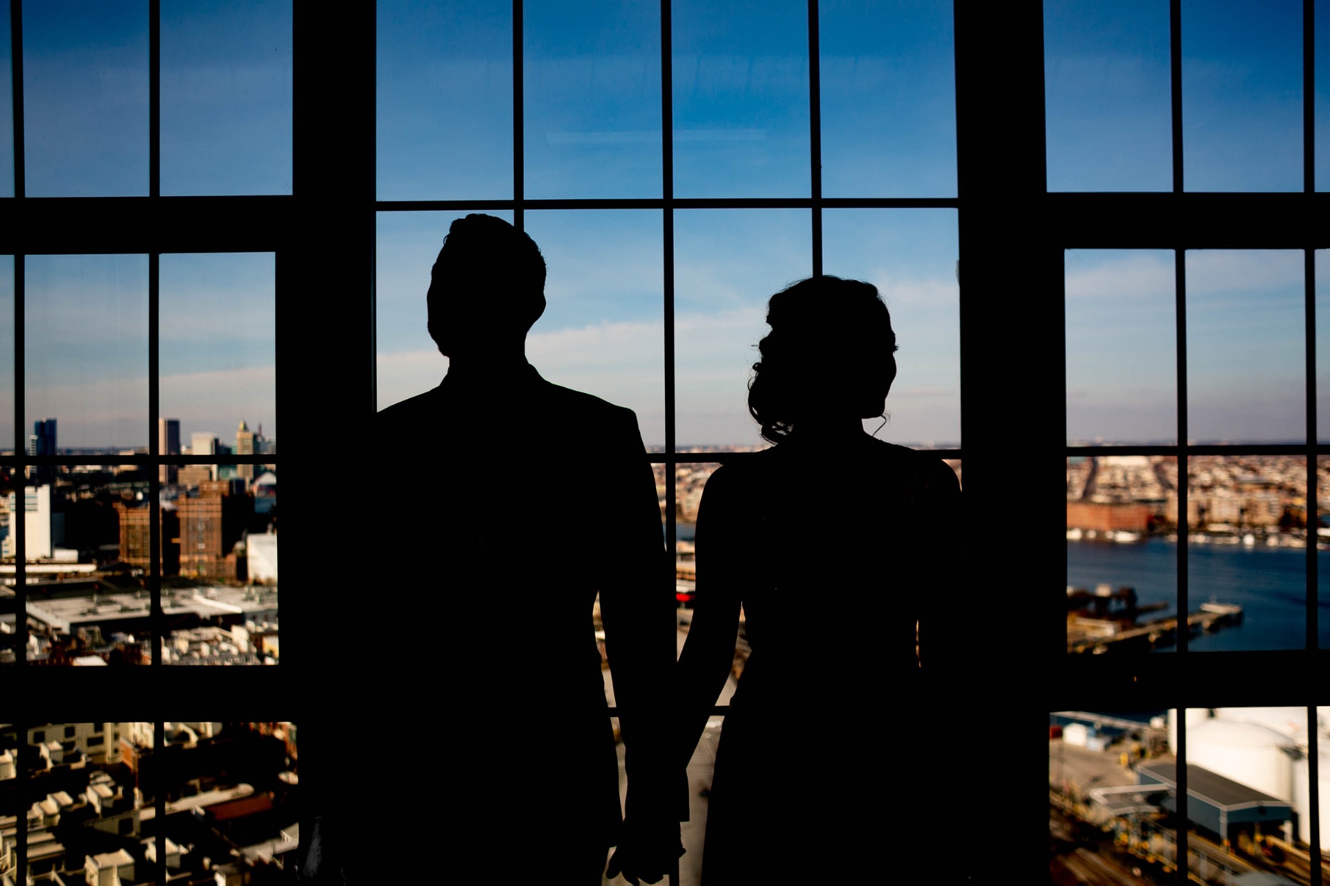 Couple silhouette holding hands industrial windows cityscape view