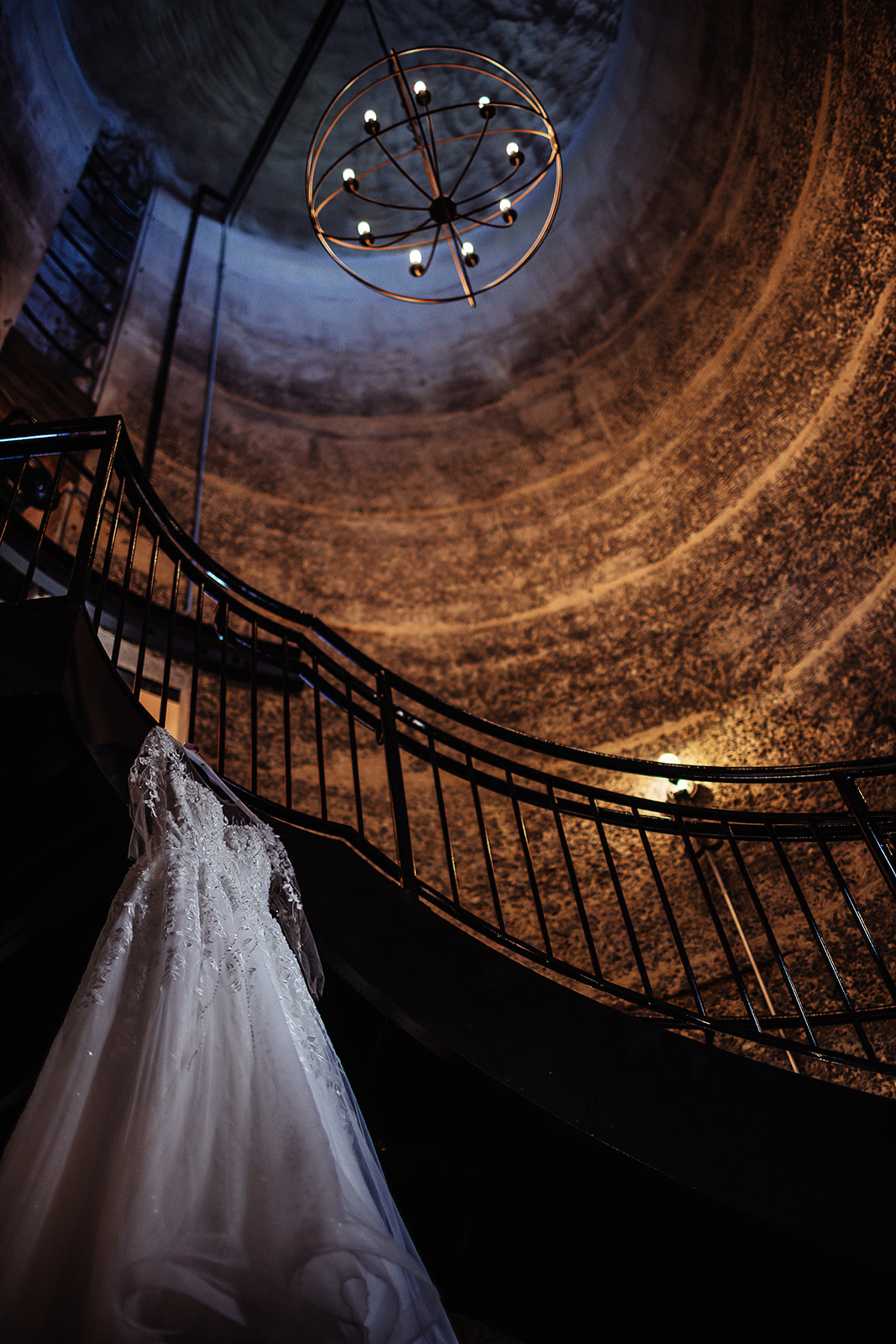 Wedding dress on spiral staircase with chandelier