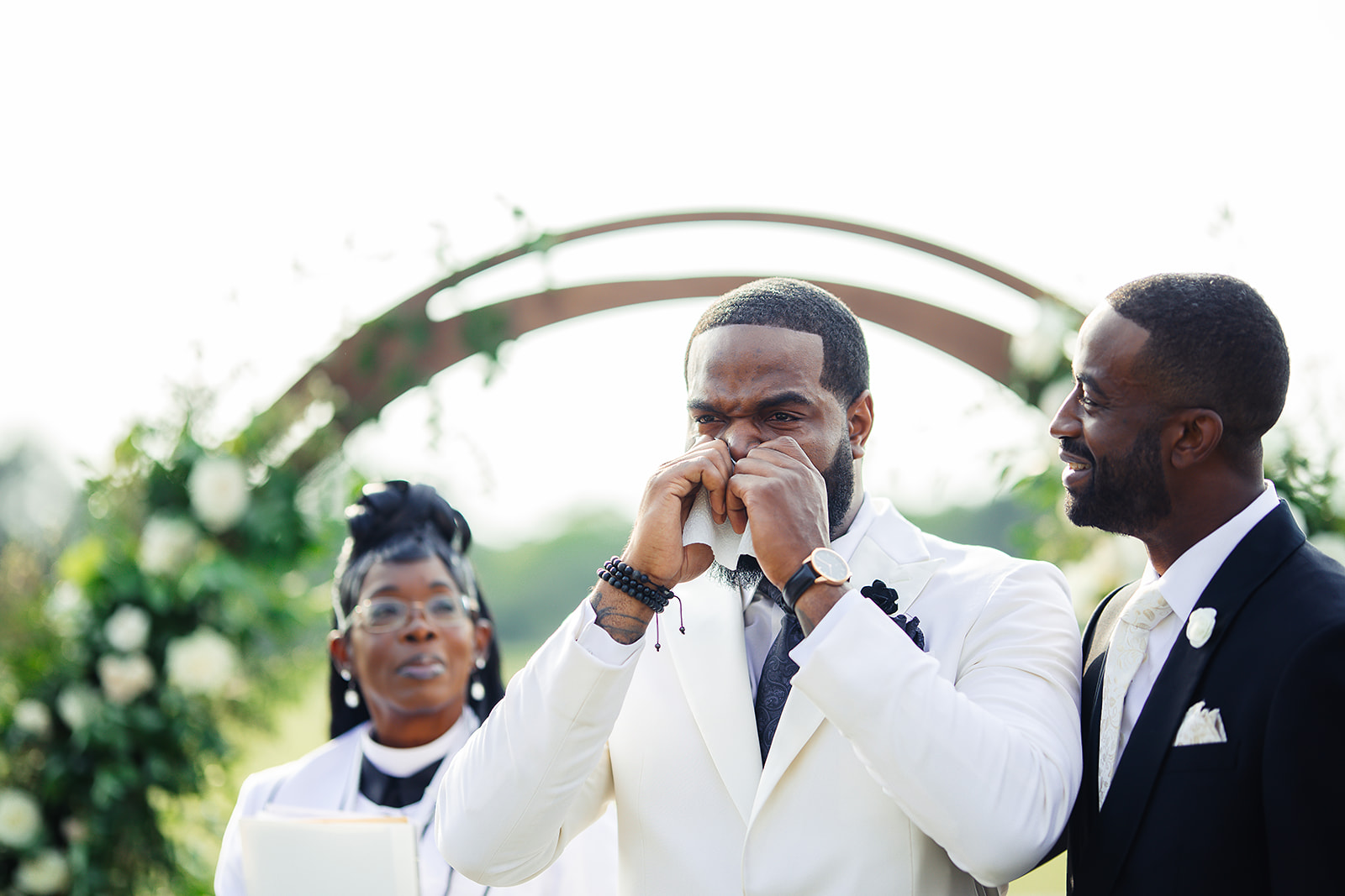 Groom emotional tears at ceremony arch with best man white jacket