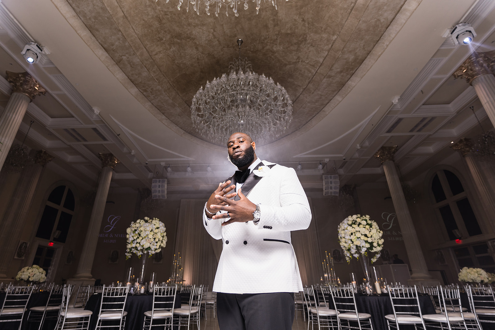 Groom in white tuxedo ballroom low angle dramatic portrait