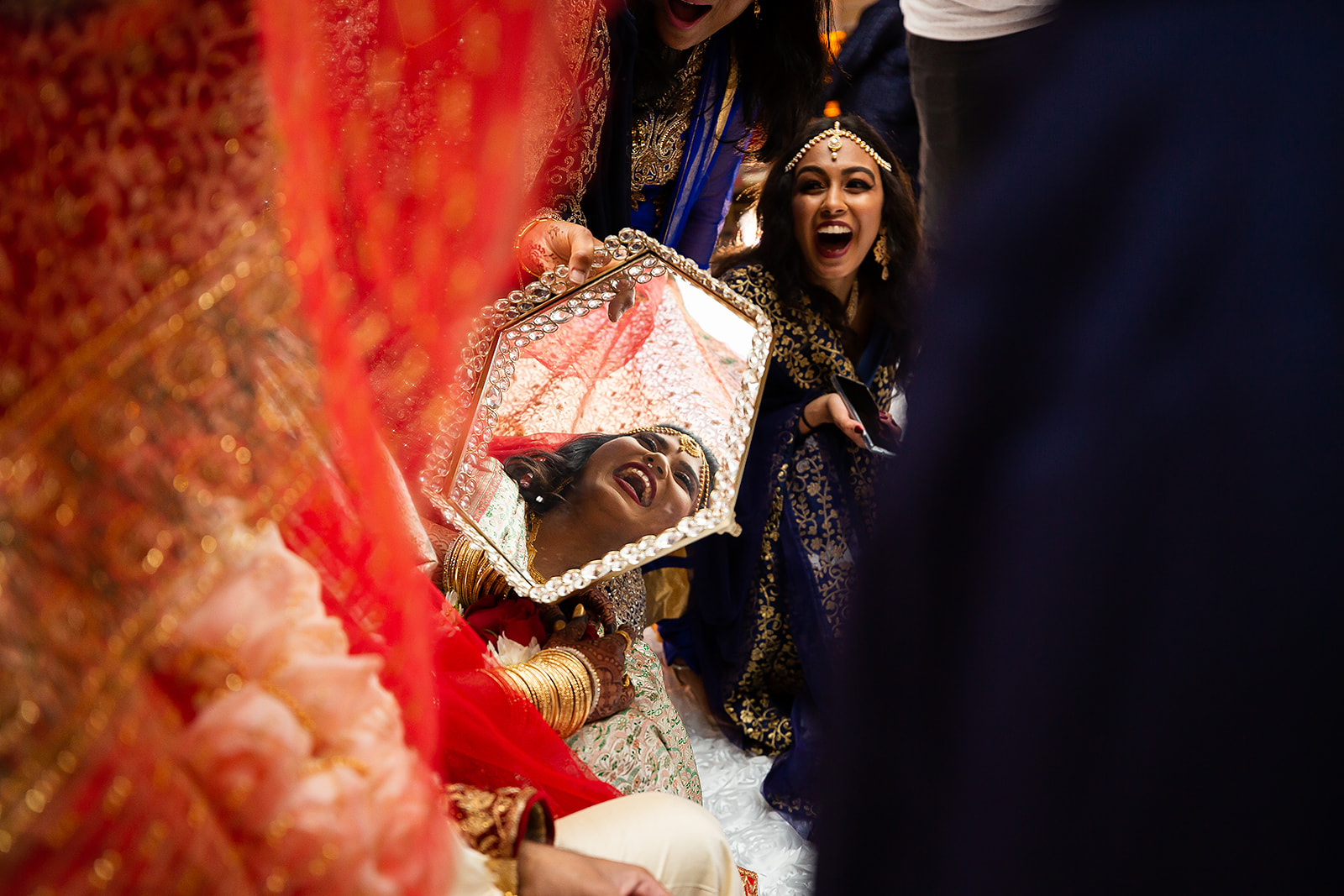 South Asian bride laughing in mirror during ceremony