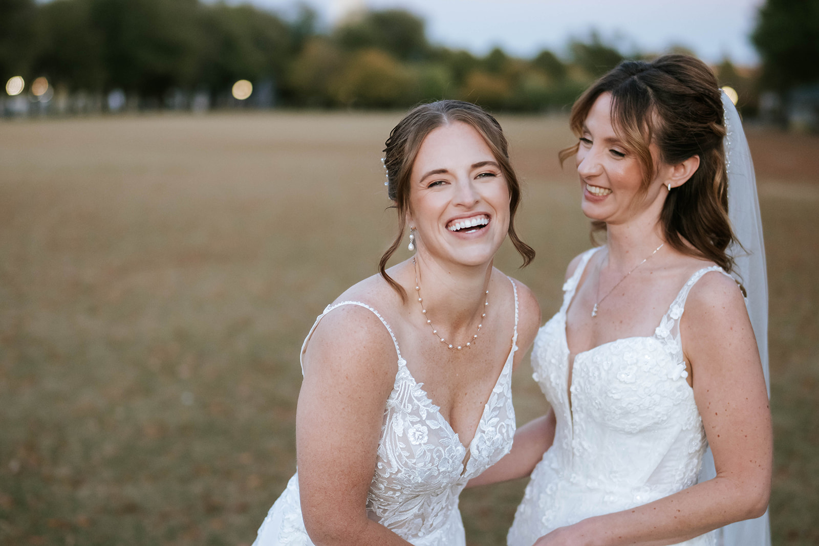 Two brides laughing in golden hour field