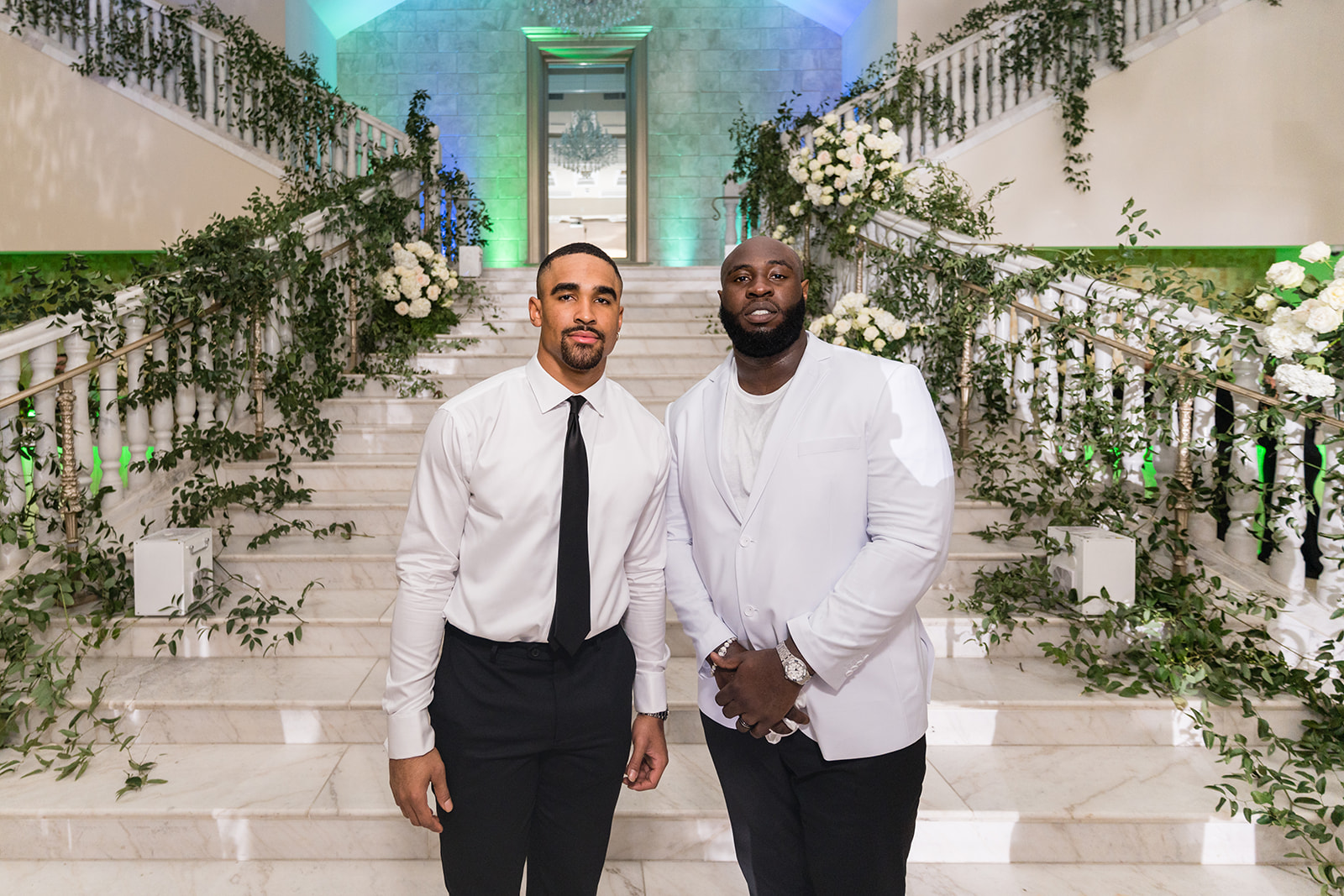 Two men on marble staircase with greenery at luxury venue